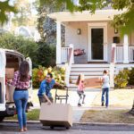 Family moving boxes from van to house.