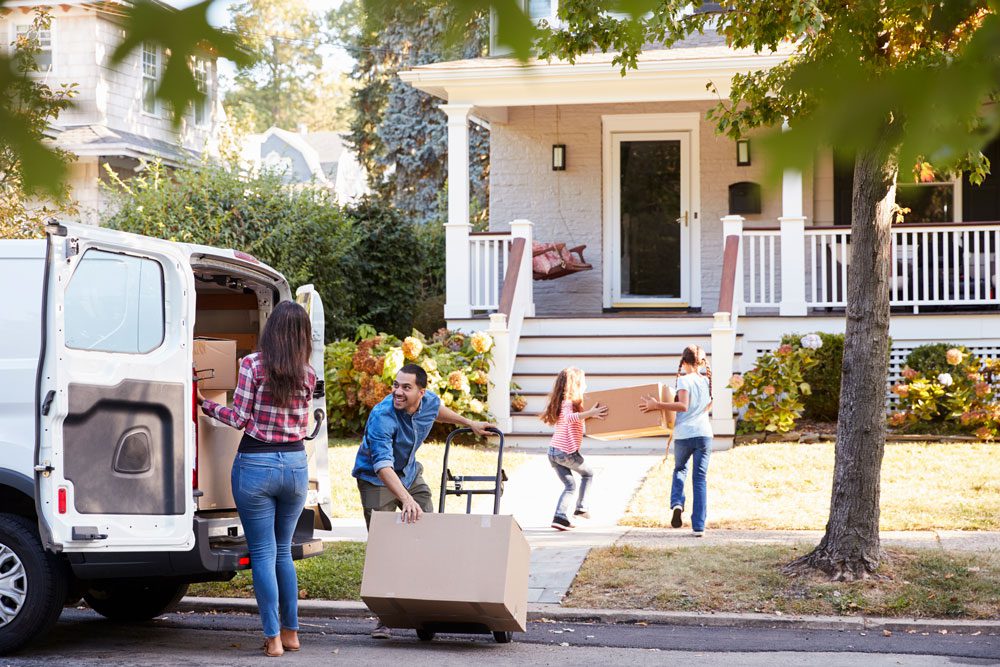 Family moving boxes from van to house.