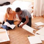 Couple assembling furniture in a living room.