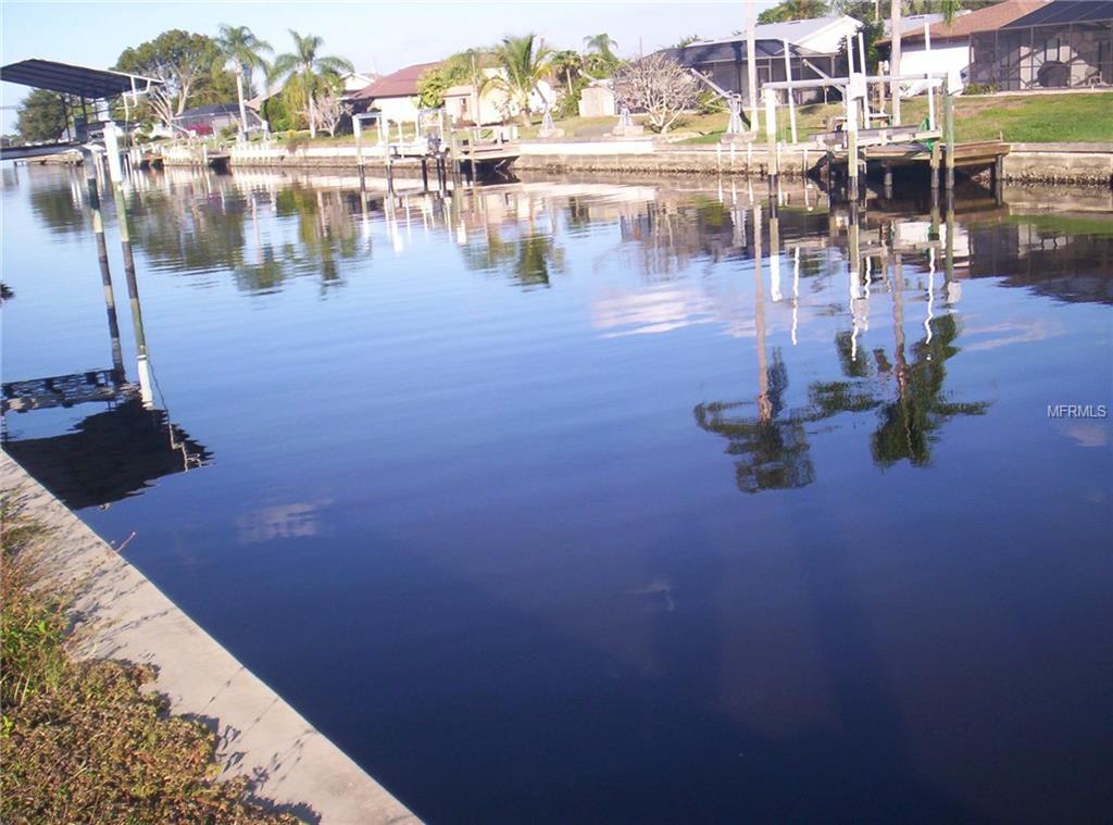 Calm water reflects homes and trees.