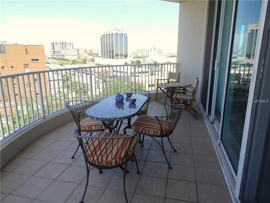 Balcony patio with table and chairs overlooking city.