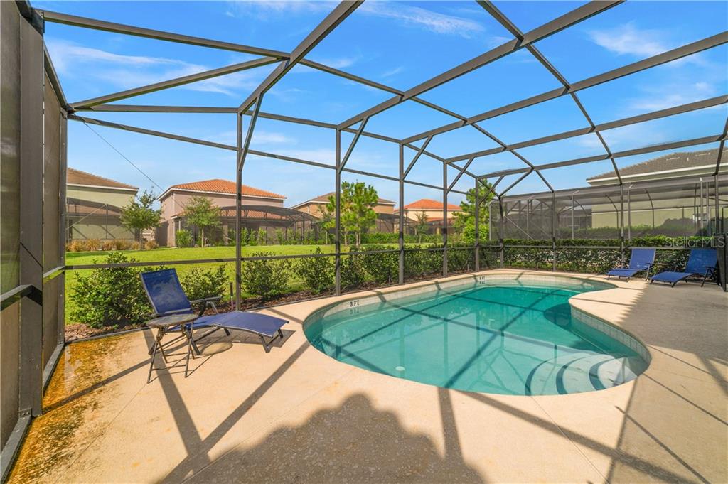 Backyard pool with lounge chairs and homes.