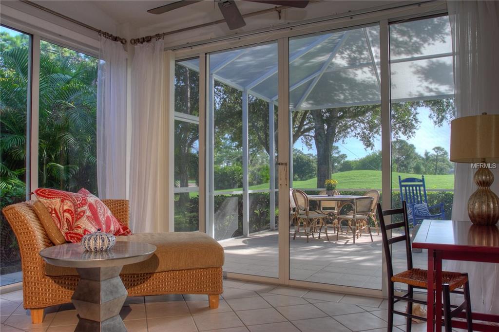 A wicker chaise lounge in a sunroom with patio doors.