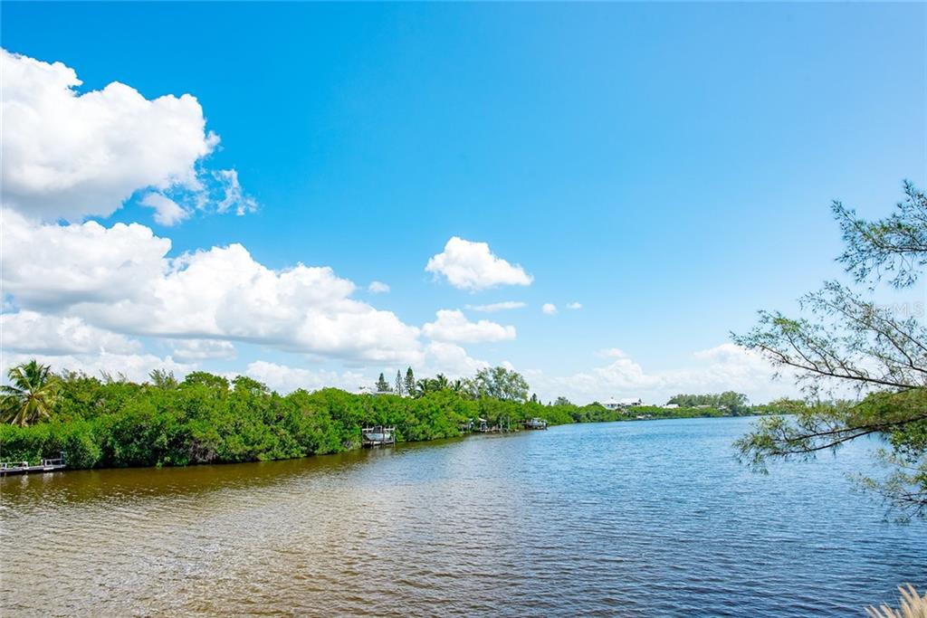 Waterway with lush greenery and blue sky.