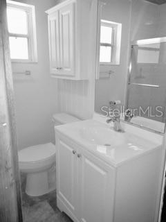 White bathroom with toilet, sink, and mirror.