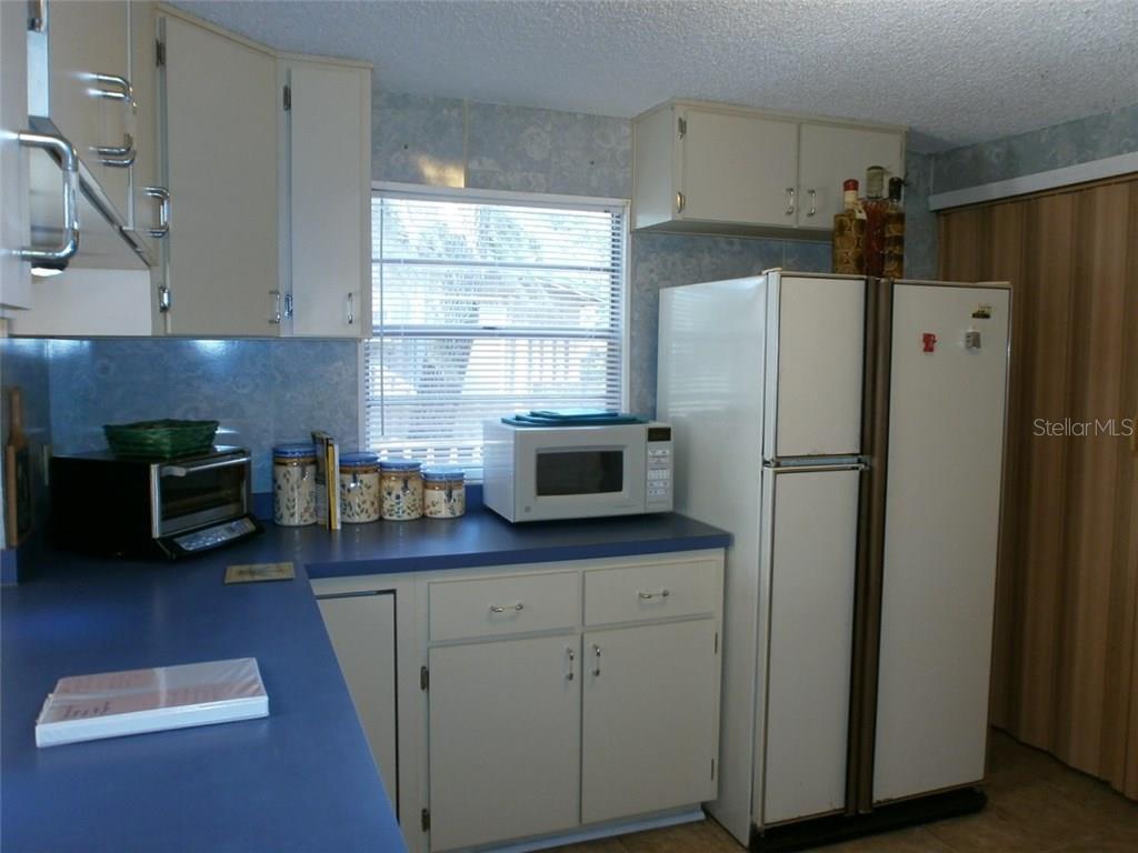 White kitchen with refrigerator and microwave.