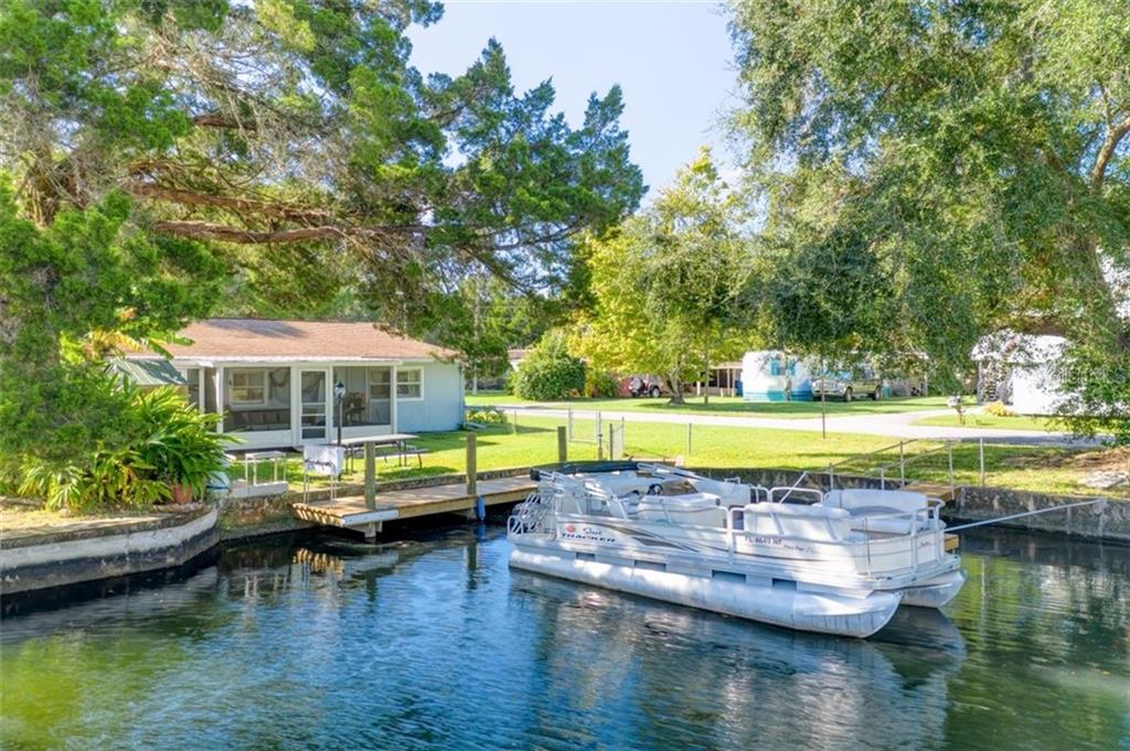 House with a dock and a pontoon boat.