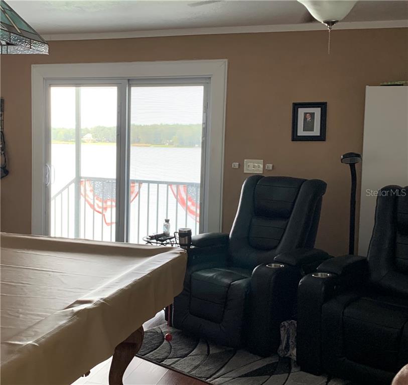 Pool table with lake view and two recliners.