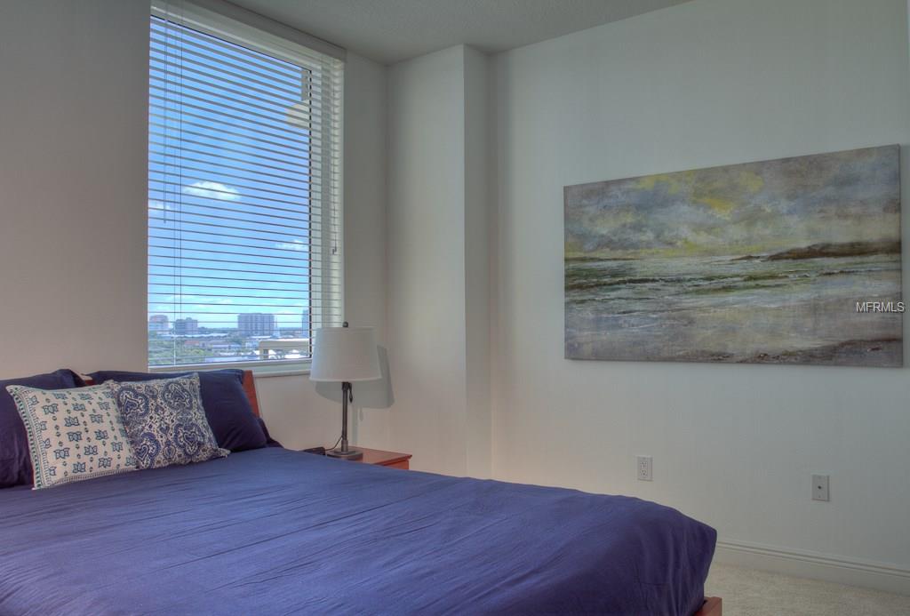 Bedroom with blue bed and ocean painting.