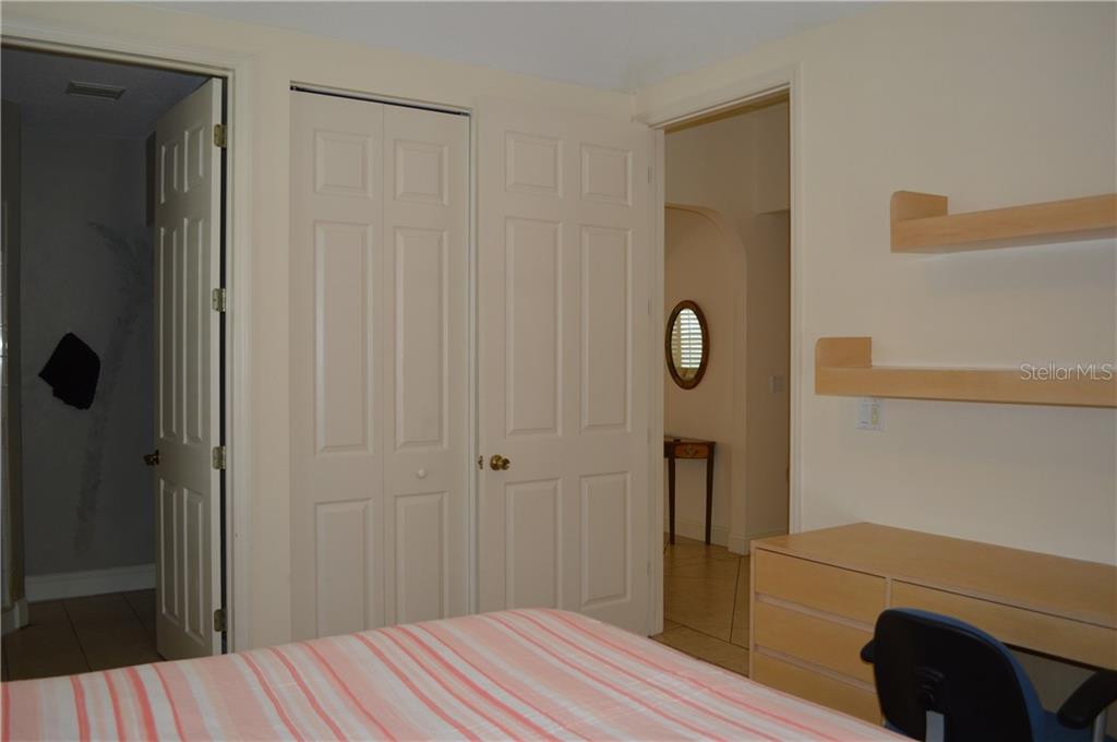 Bedroom with white doors, shelves, and bed.