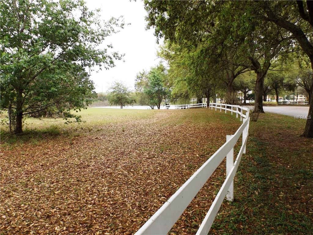 White fence along a grassy field with trees.