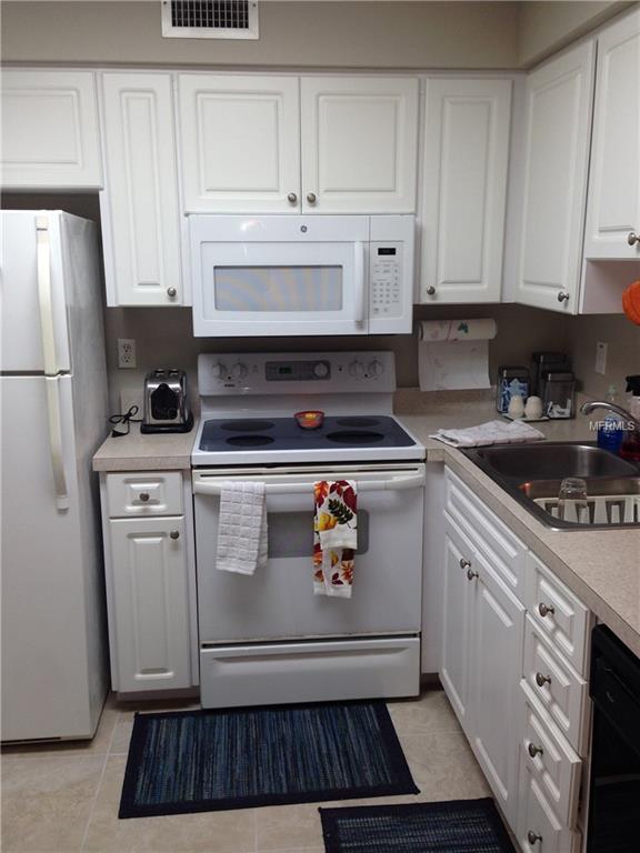 White kitchen with oven, microwave, and fridge.