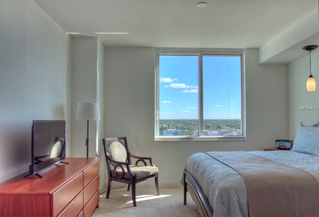 Modern bedroom with city view and bed.