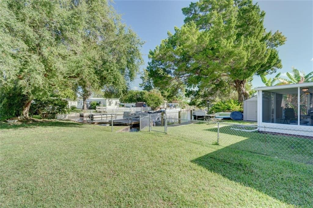 Green lawn with fenced backyard and canal.