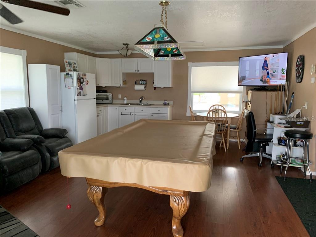 Pool table in a living room with kitchen in background.