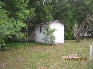 A small white shed in a grassy yard.