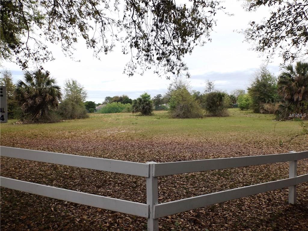 Empty grassy field with a white fence.