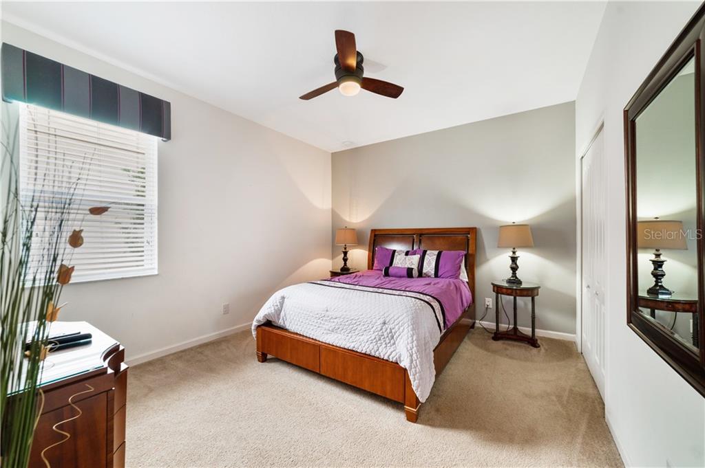 Bedroom with a bed, lamp, and ceiling fan.