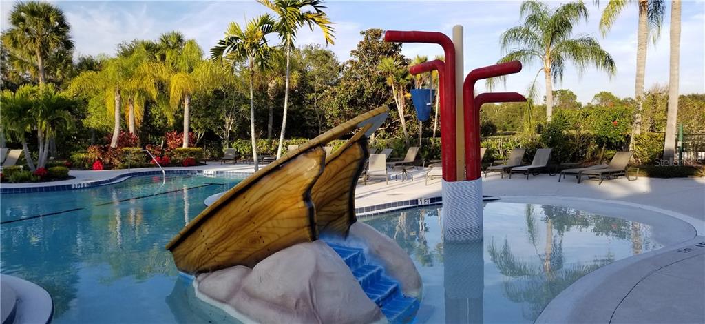 Wooden ship slide in pool with palm trees.