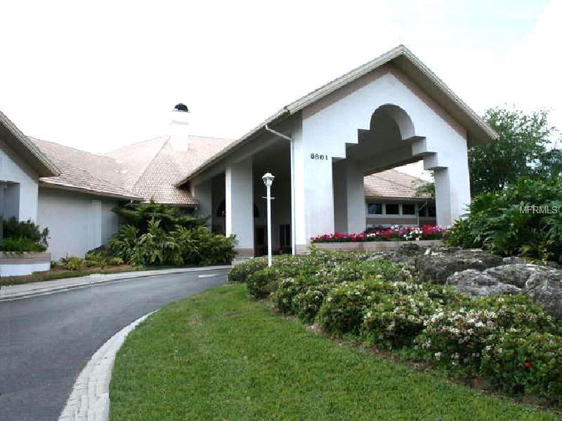 White building with arched entrance and landscaping.