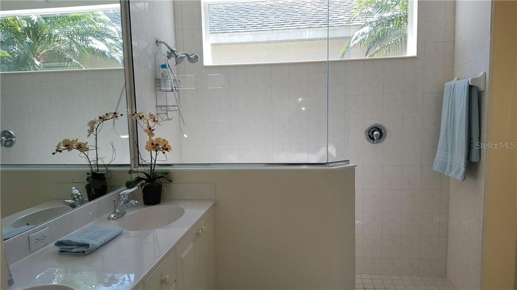 White bathroom with double sinks and shower.