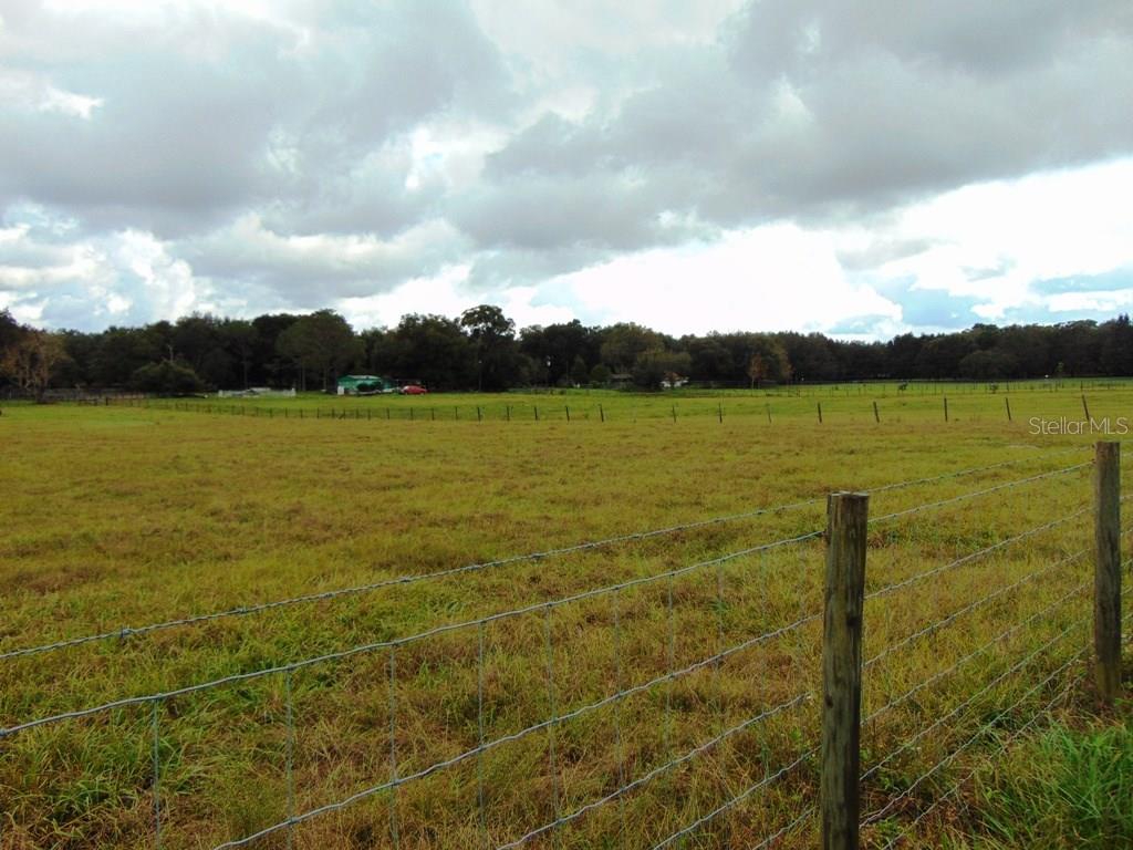 Fenced grassy field with cloudy sky.