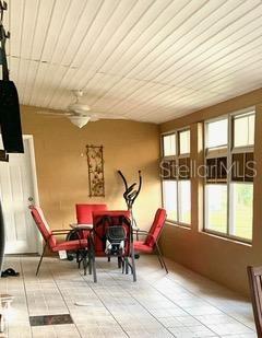 A furnished sunroom with tiled floors.