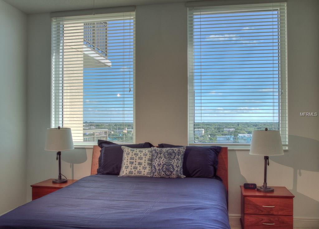 Bed with blue bedding and city views.