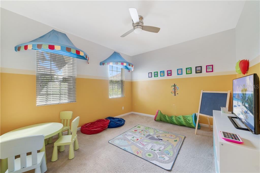 Playroom with a ceiling fan, TV, and toys.