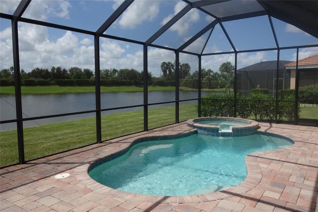 A screened pool and spa overlooking a lake.