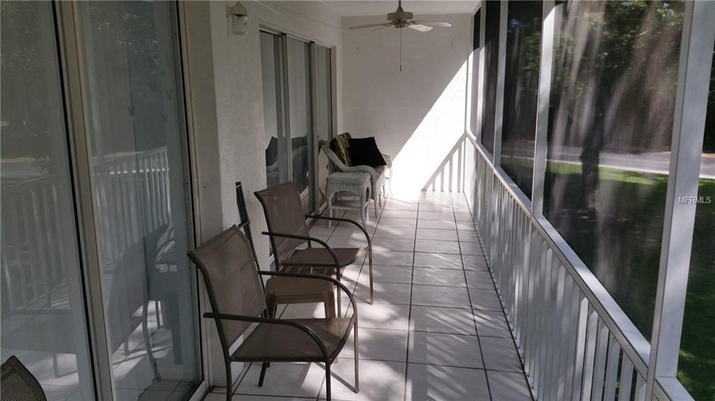 Screened porch with patio furniture and a fan.