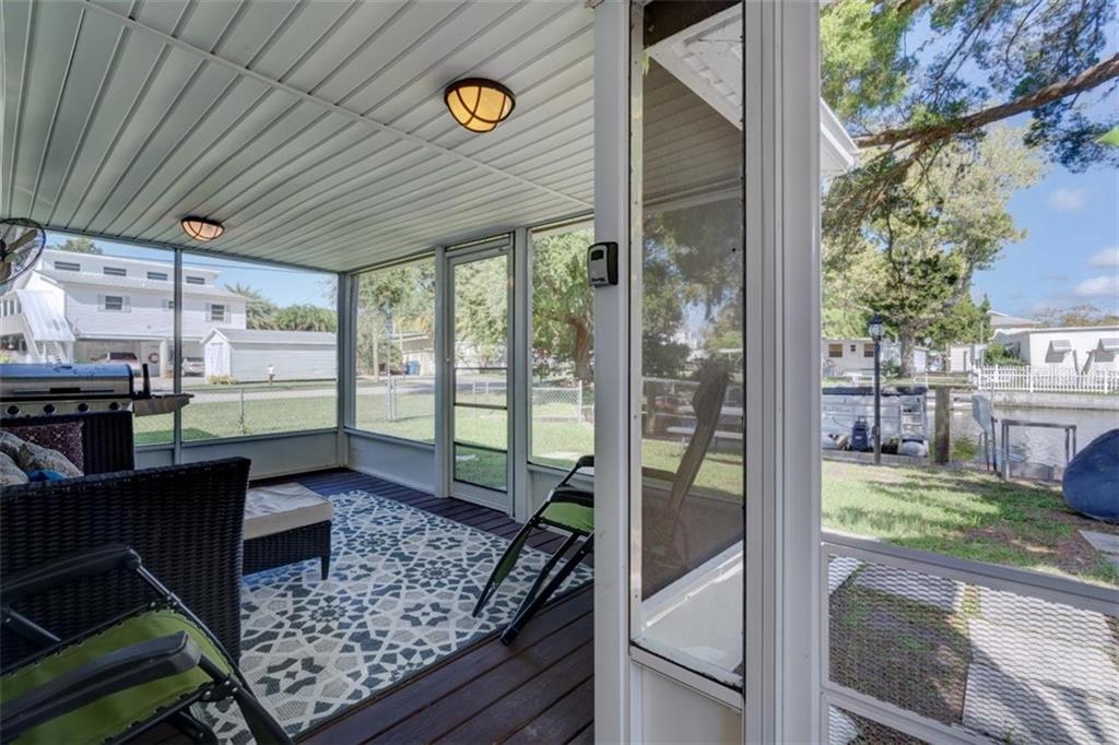 Screened porch with furniture and a view of the water.