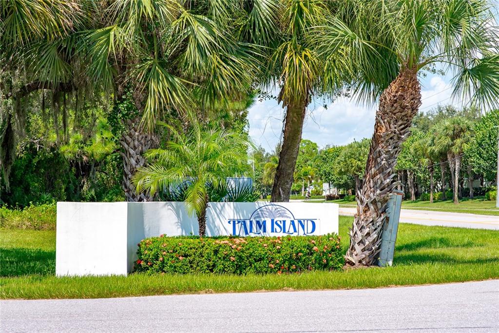 Palm Island sign with lush greenery.