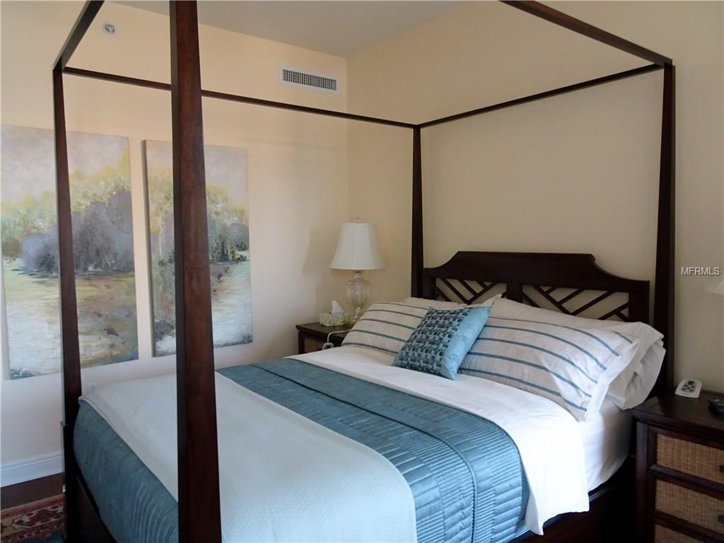 Four-poster bed with blue bedding and paintings.