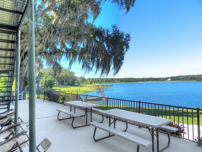 Two picnic tables by a lake with trees.