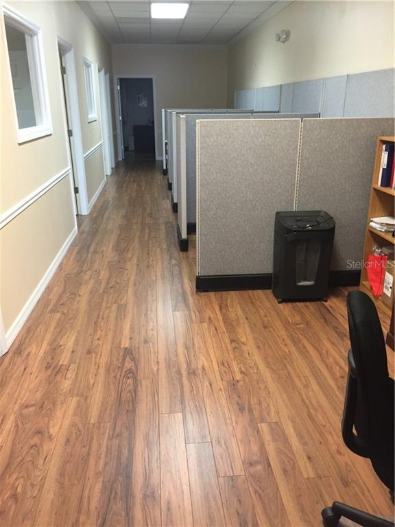 Office hallway with wood floor and cubicles.