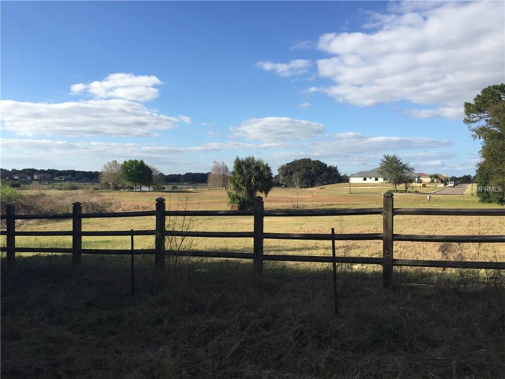 A wooden fence in front of a grassy field.