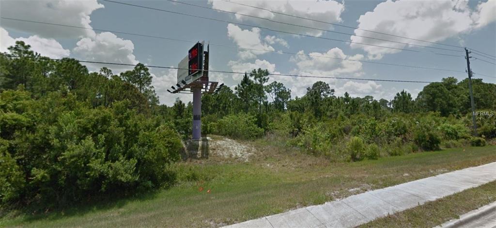 Vacant lot with billboard and trees.