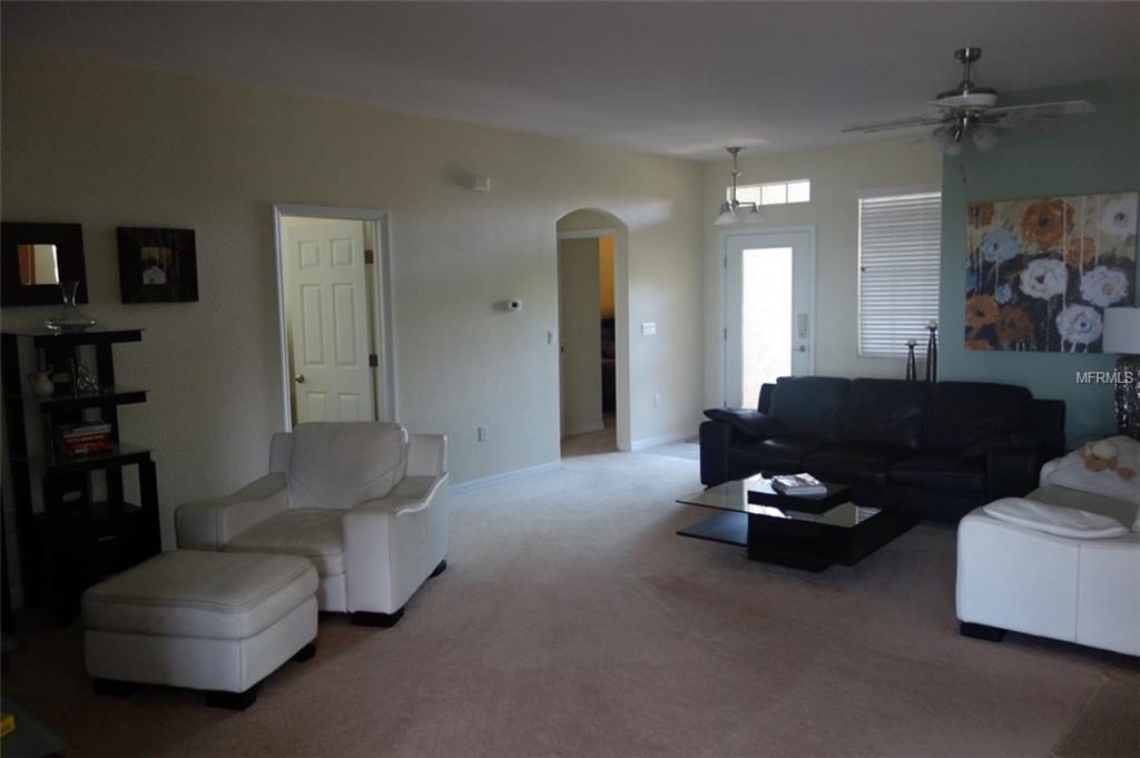 Living room with white furniture and black couch.