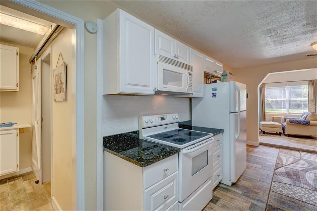 White kitchen with black granite countertops.