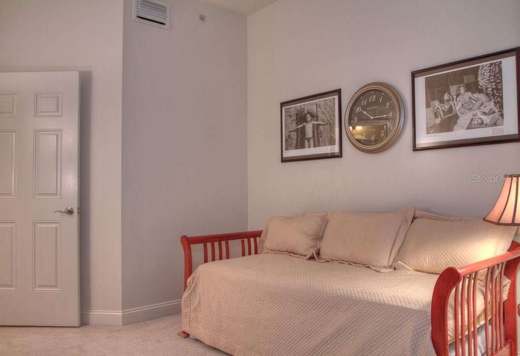 Red daybed with tan bedding and pillows.