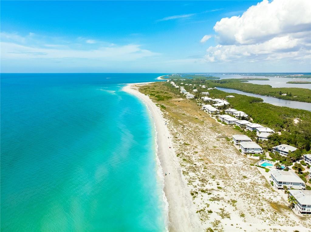 Aerial view of a white sand beach with blue water.