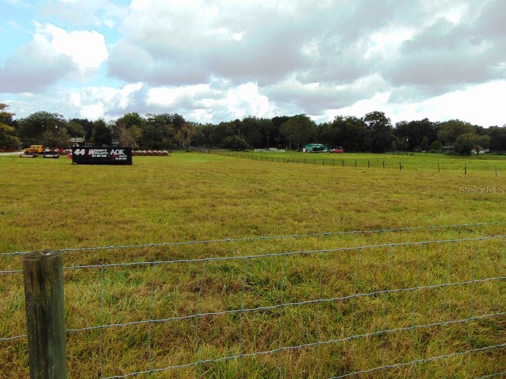 Fenced field with hay bales and trucks.