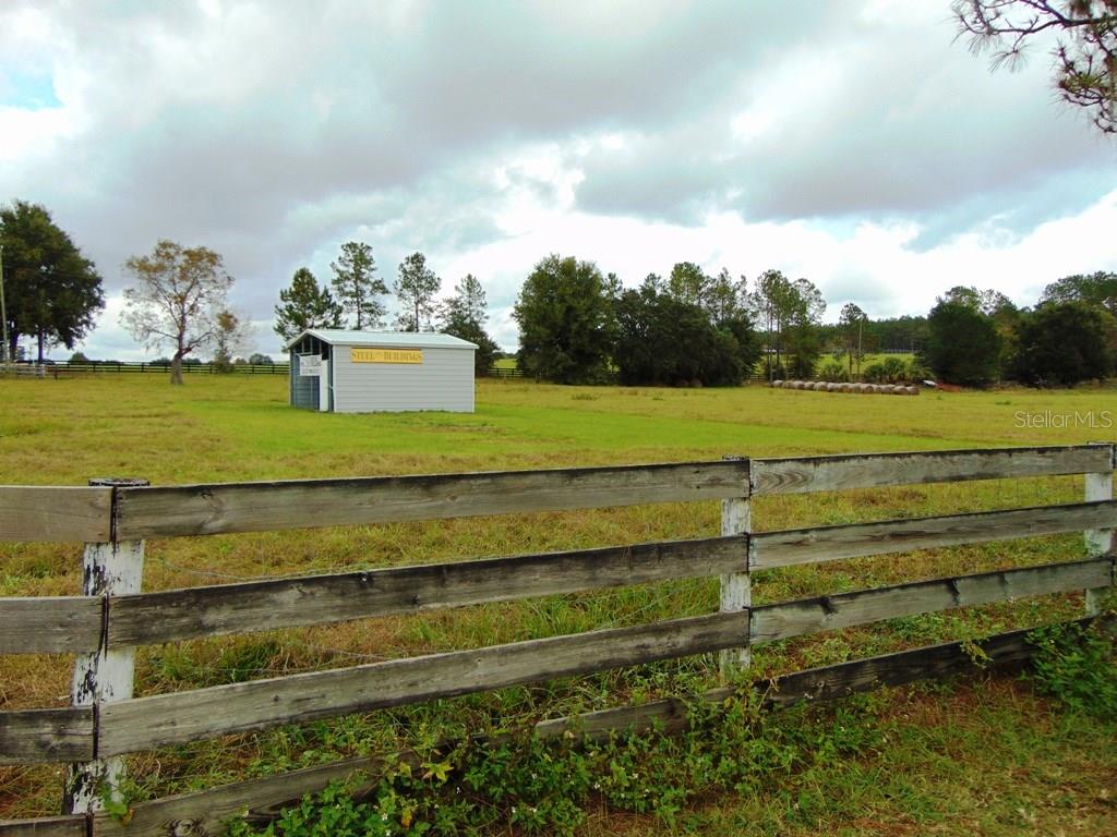 Wooden fence in a grassy field with a shed.