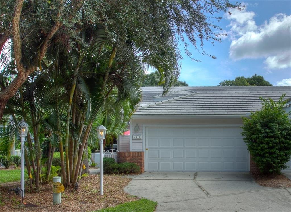 White house with garage and palm trees.