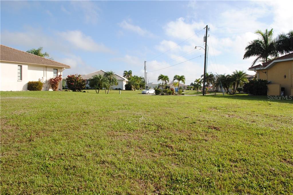 Green grassy lot with houses in background.