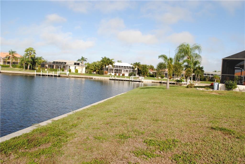 A waterfront view with houses and palm trees.