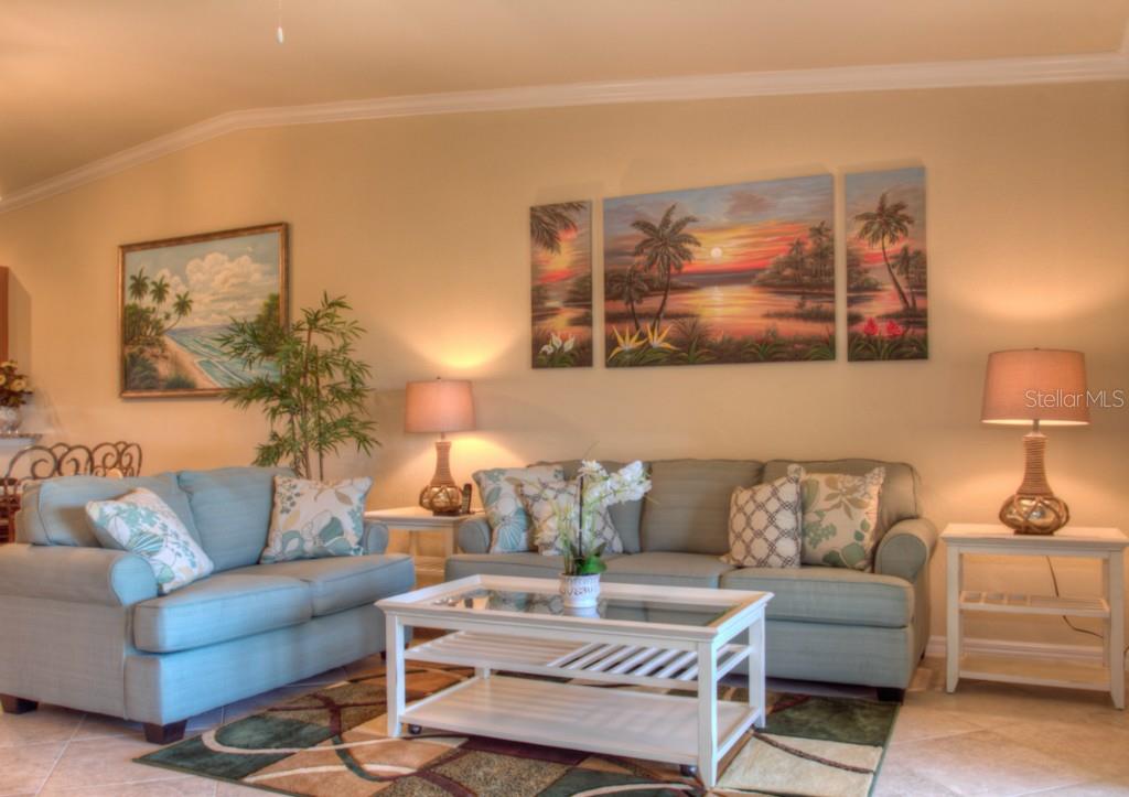 Living room with blue couches and tropical artwork.