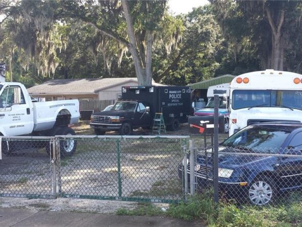 Cars parked behind a chain-link fence.