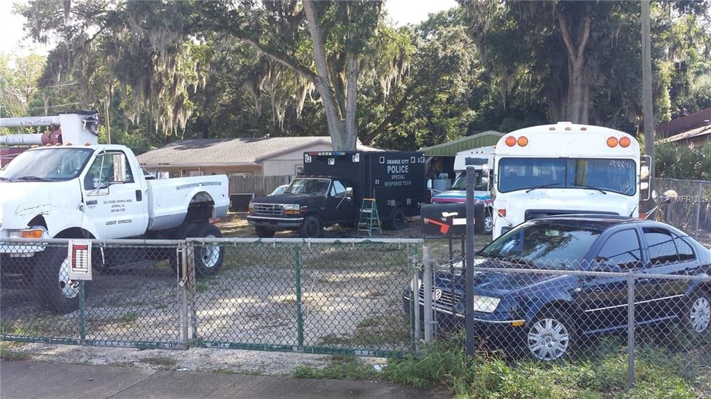 Vehicles parked behind a chain-link fence.